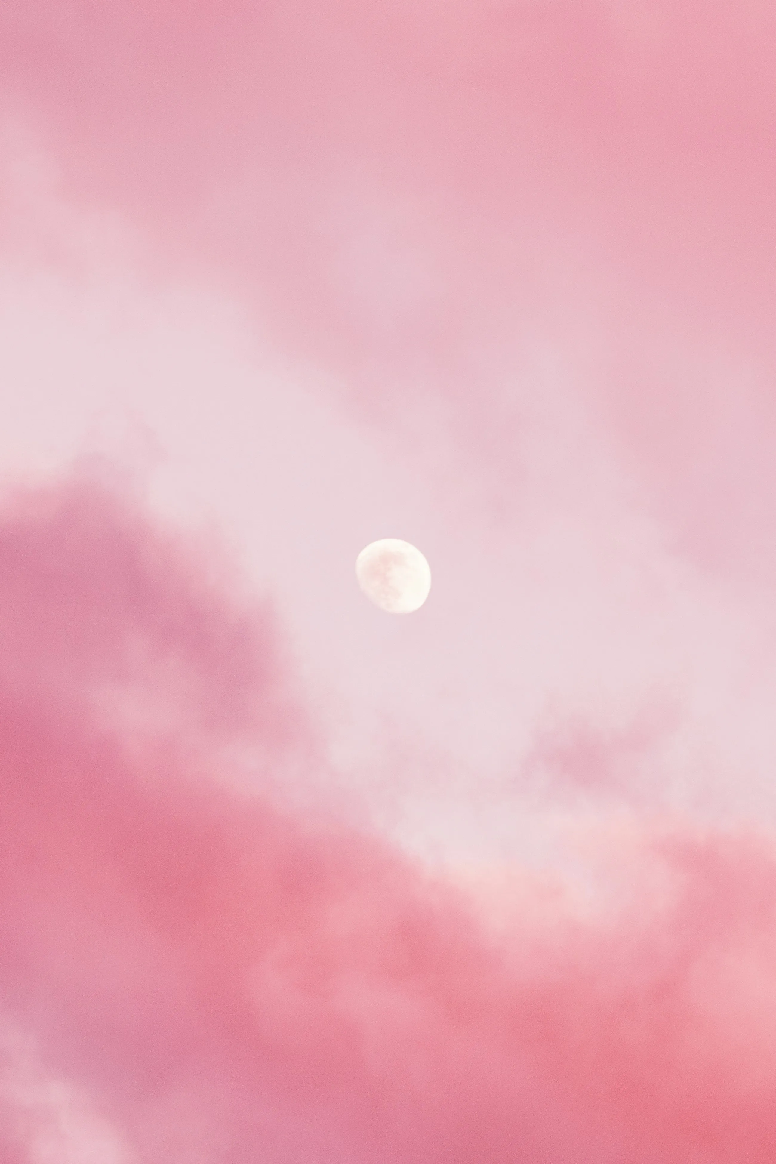 A pink evening sky with the moon showing through thin cloud