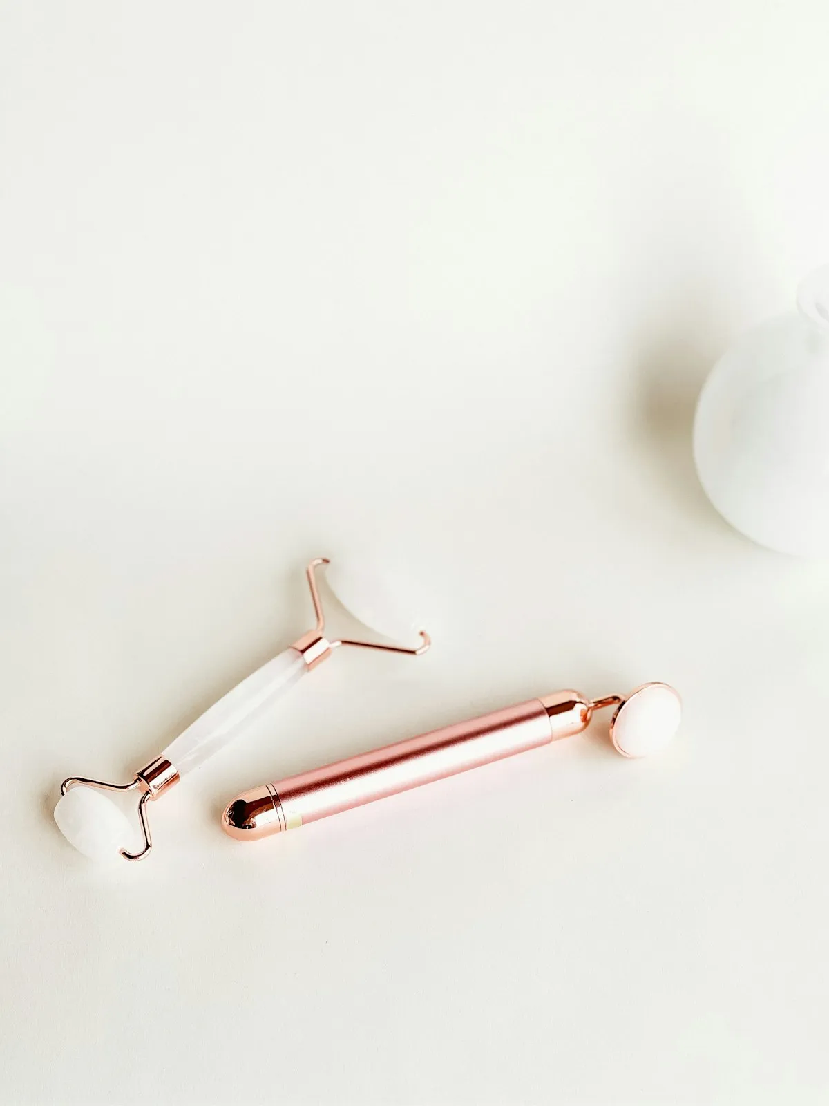 A rose-gold face roller lying on a white surface