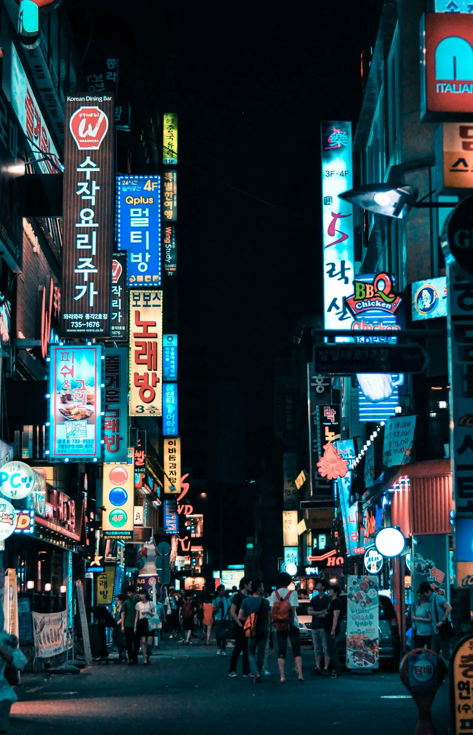 A narrow Seoul street at night lined with stacked neon signs